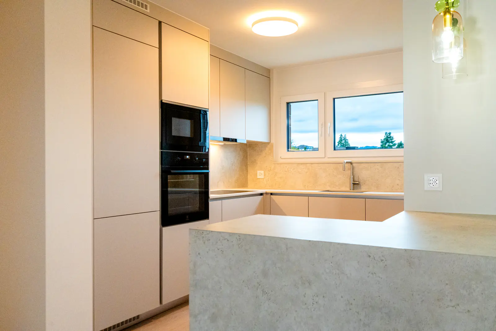 Massgefertigte Küche mit Dekton-Bar in Steinoptik und Fenster mit Weitblick – Umbau in Thalwil