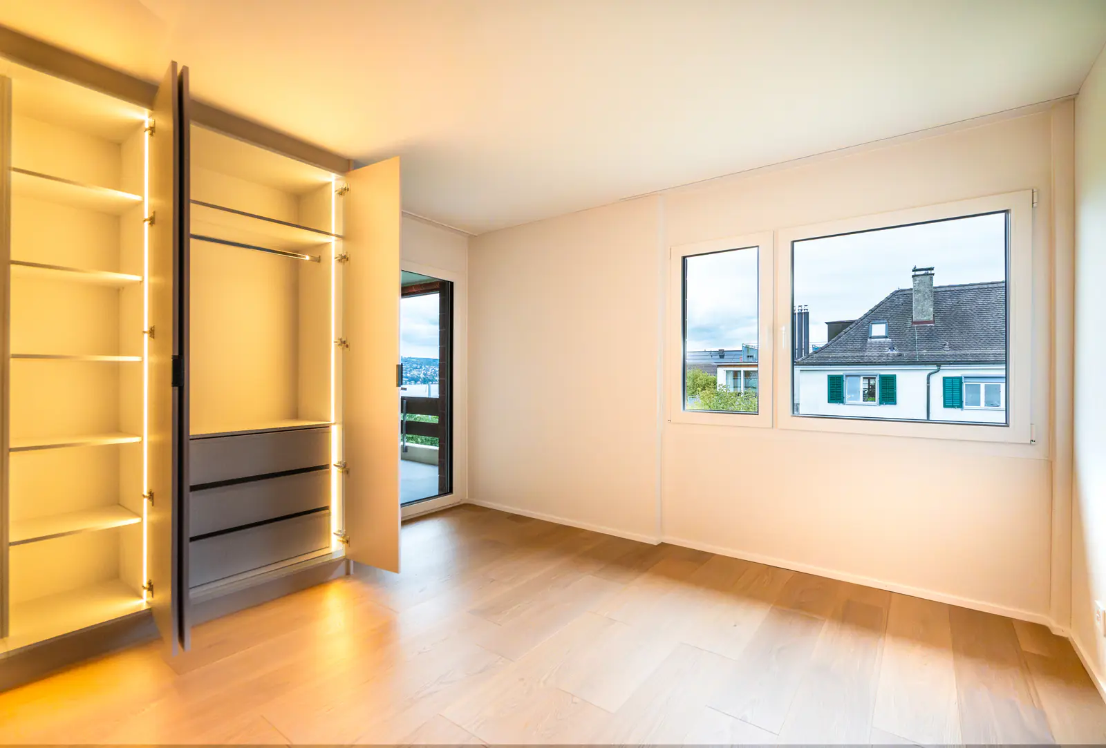 Zimmer mit deckenhohem, beleuchtetem Einbauschrank und Eichendielen – Umbau in Thalwil