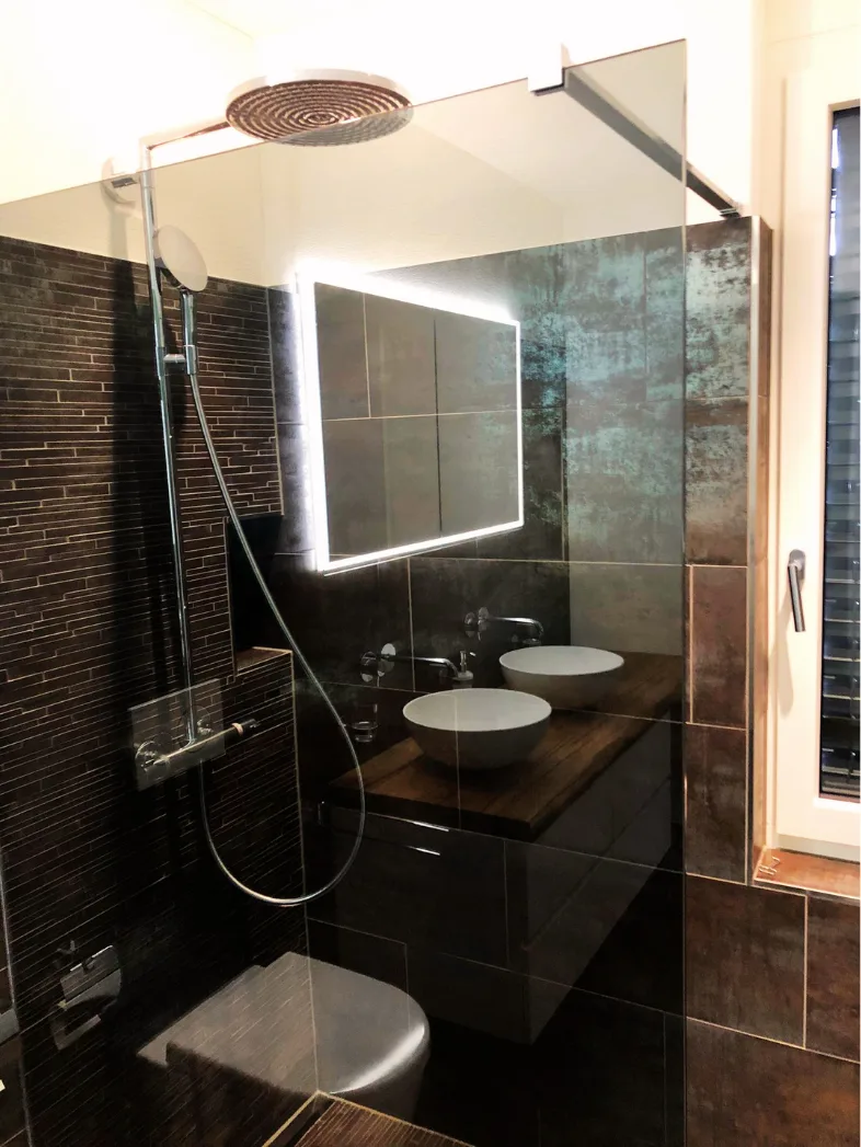 Badezimmer mit Walk-in-Regendusche und dunklen Platten – Neubauwohnung Zürich