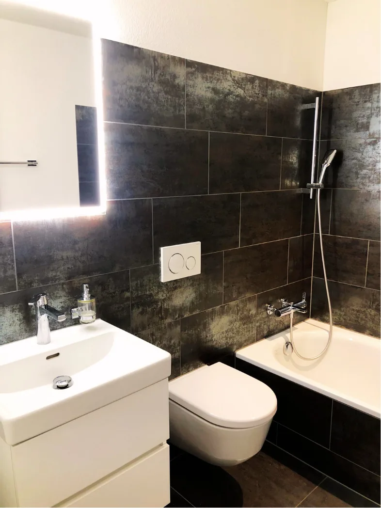 Badezimmer mit Badewanne und beleuchtetem Spiegel – Neubauwohnung Zürich