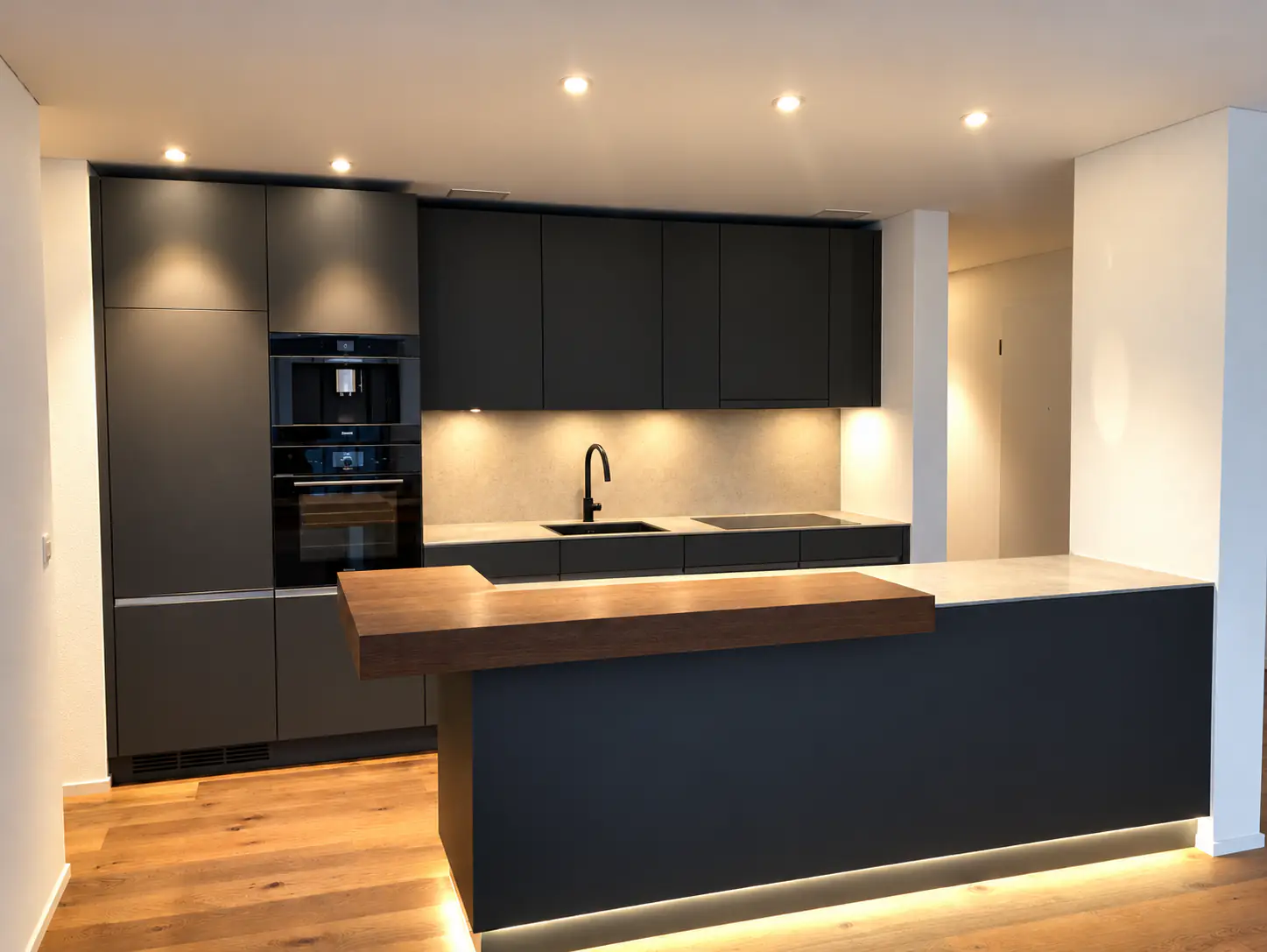 Designküche in Anthrazit mit Holztheke und indirekter Beleuchtung – Neubauwohnung in Zürich, ARTIAS Group