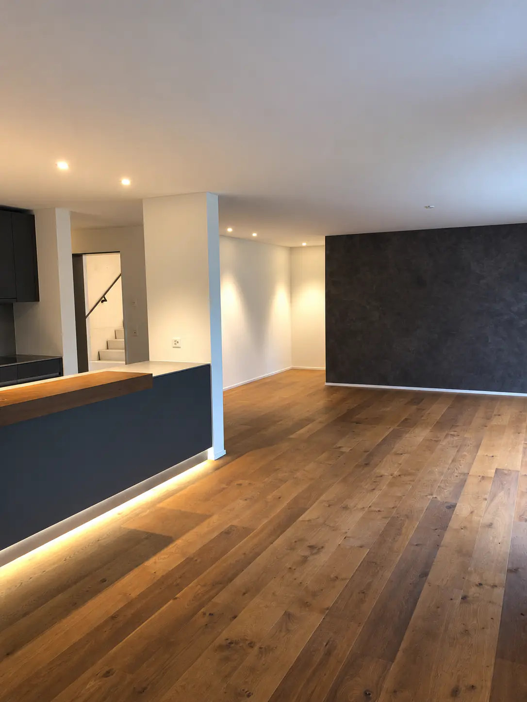 Offener Wohnraum mit Kücheninsel und Eichenparkett – Neubauwohnung Zürich