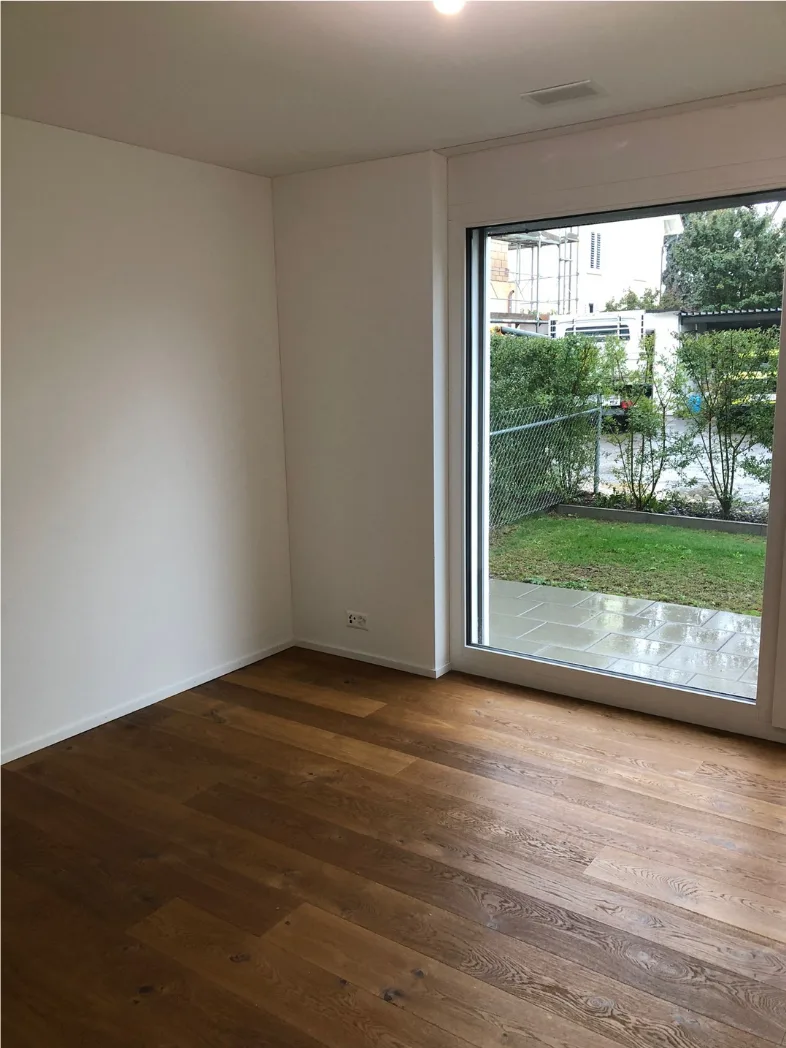 Helles Zimmer mit Eichenparkett und Blick in den Garten – Neubauwohnung Zürich
